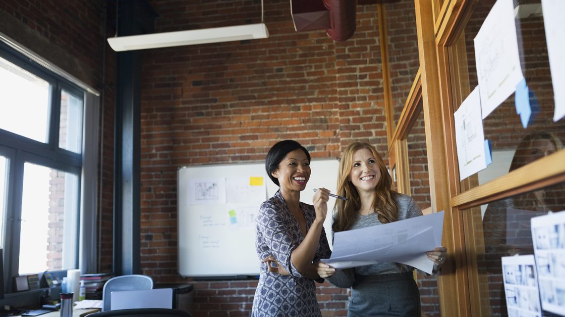 Businesswomen reviewing paperwork in office - The State of Women